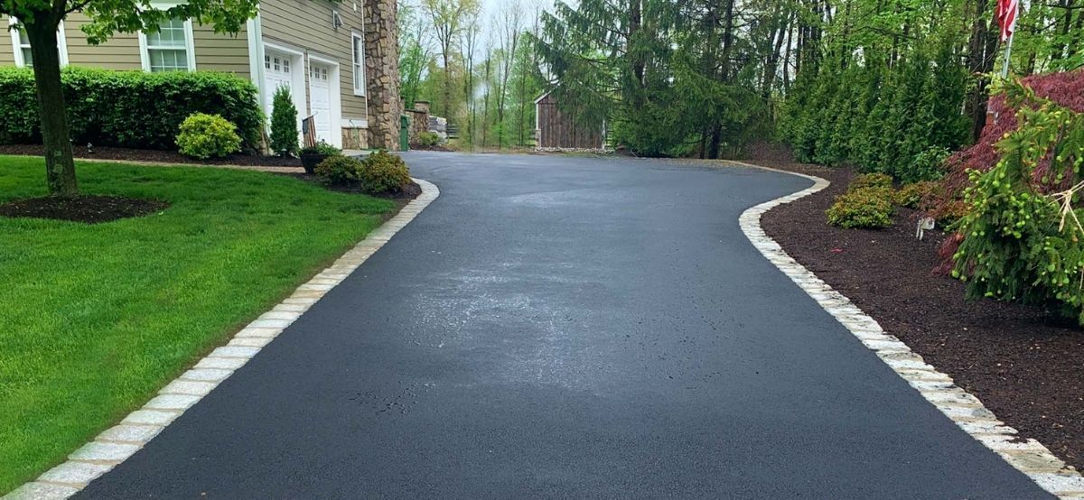 An asphalt driveway with clean lines and a smooth surface, leading from the road to the house.