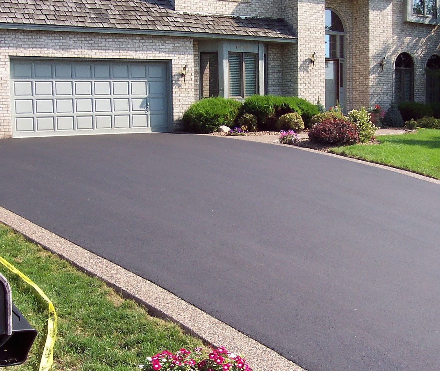 An asphalt driveway, neatly outlined with crisp edges and a smooth, dark surface.