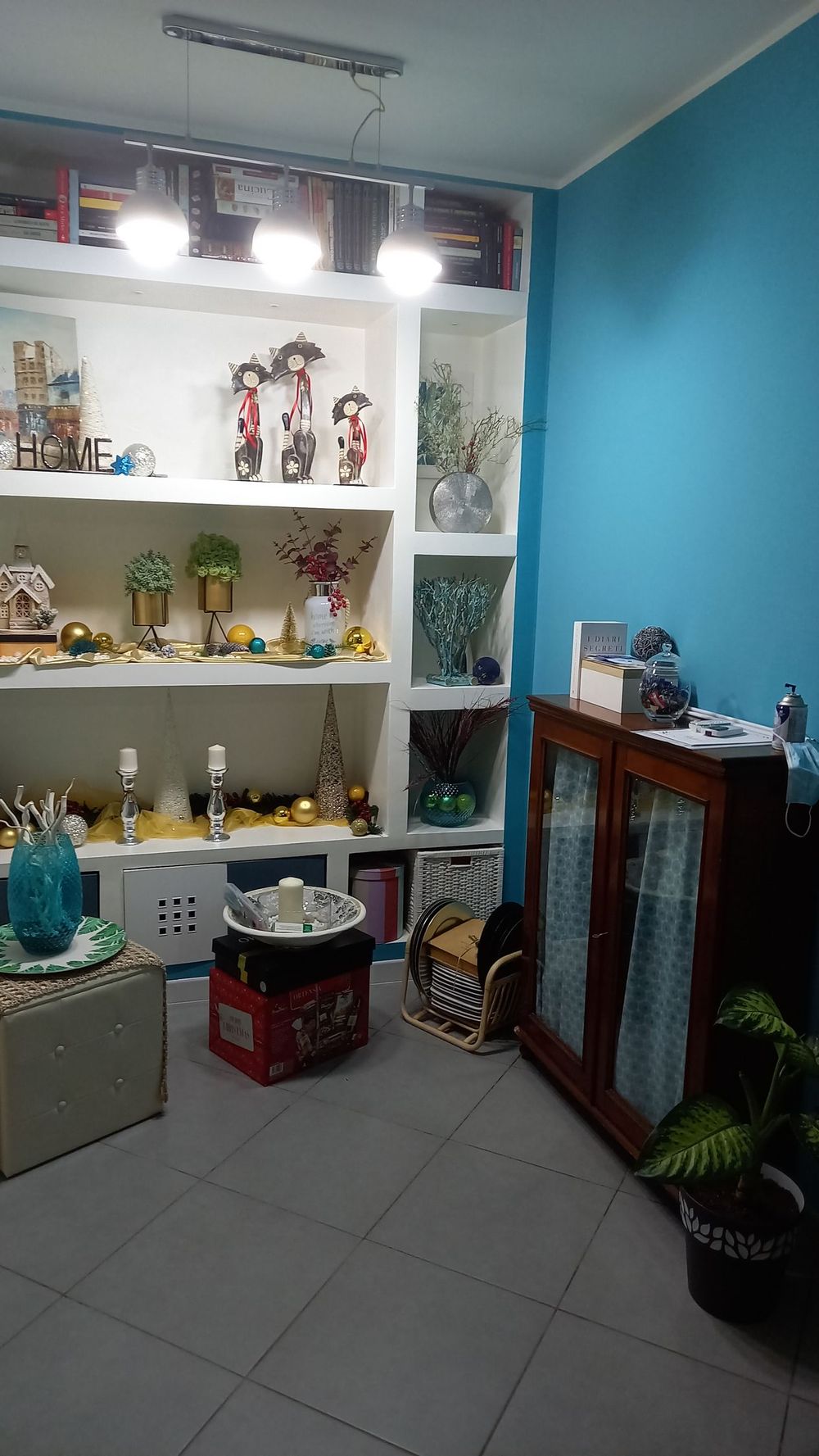 Piccolo negozio di articoli da regalo con scaffali pieni di statuette, pareti blu, vetrine e oggetti decorativi.