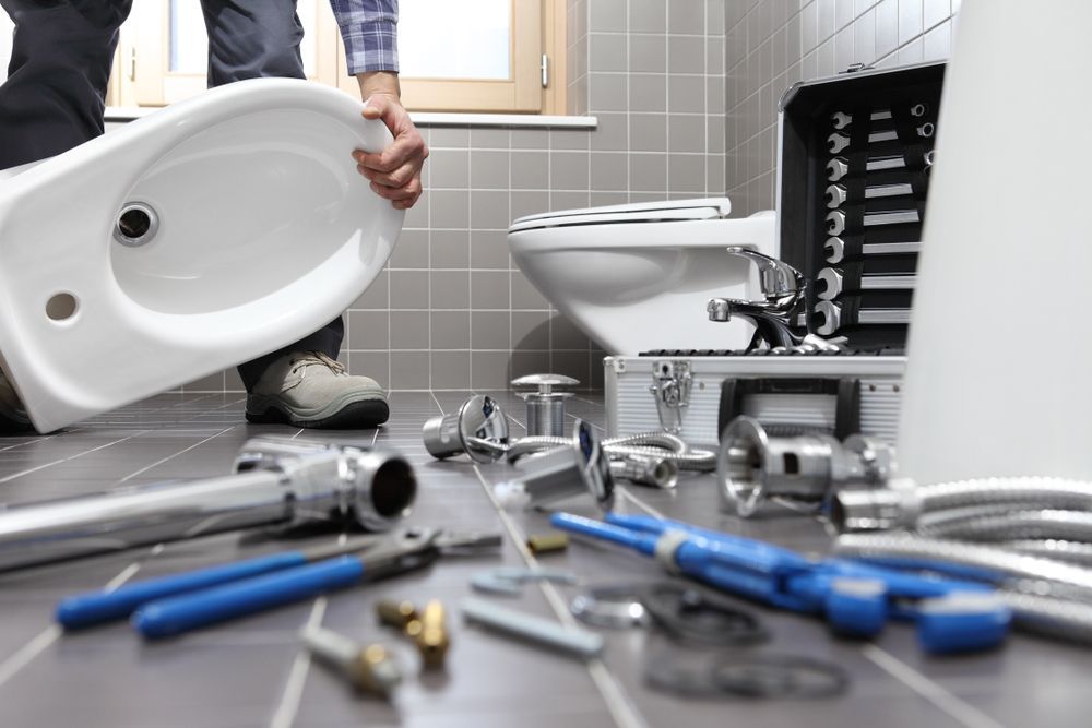 Plumber Installing a White Bidet in a Bathroom With Tools — Zac Rennick Plumbing in Wellington, NSW