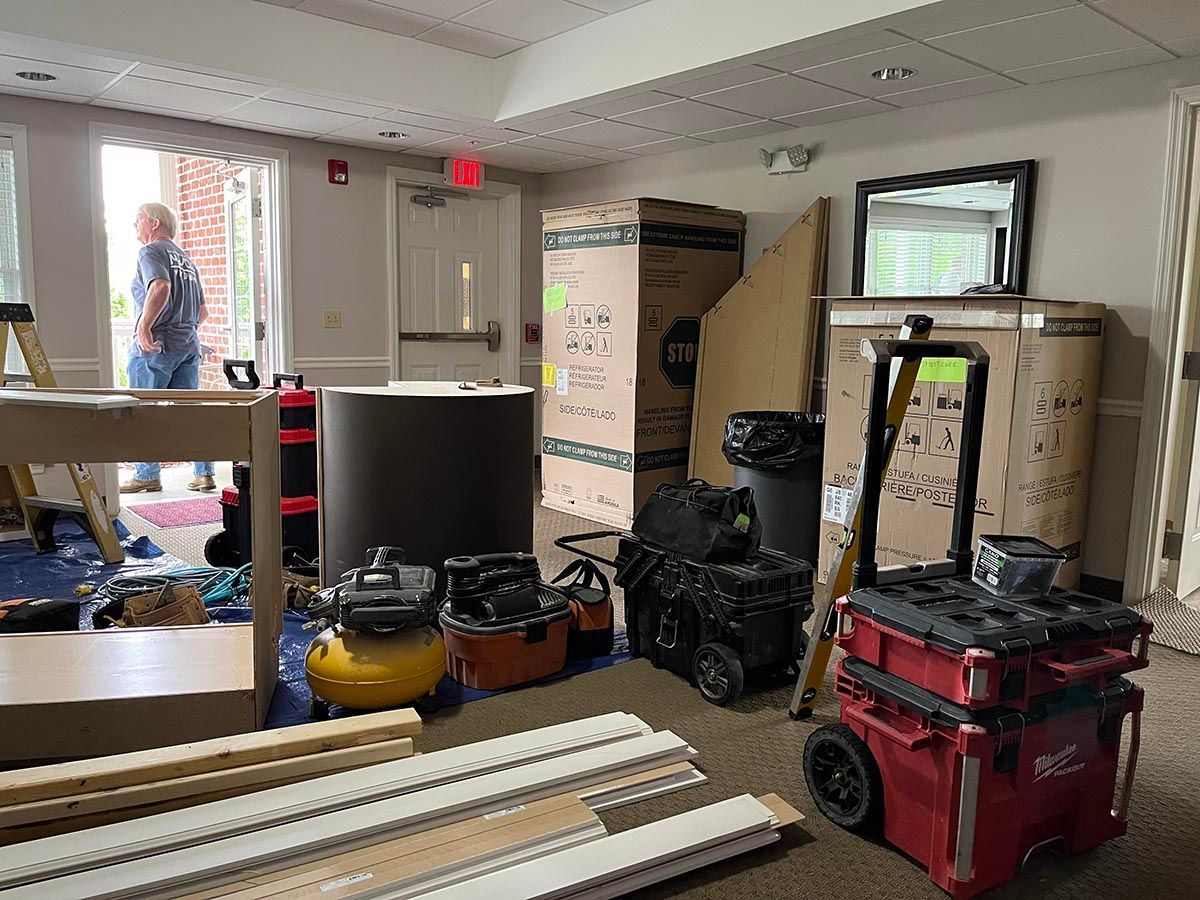 A man is standing in a room filled with boxes and tools.