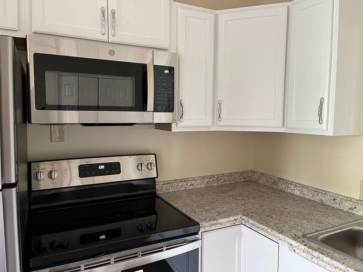 A kitchen with a stove , microwave , refrigerator and sink.