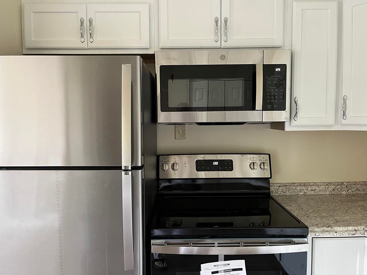 A kitchen with a refrigerator , stove and microwave.
