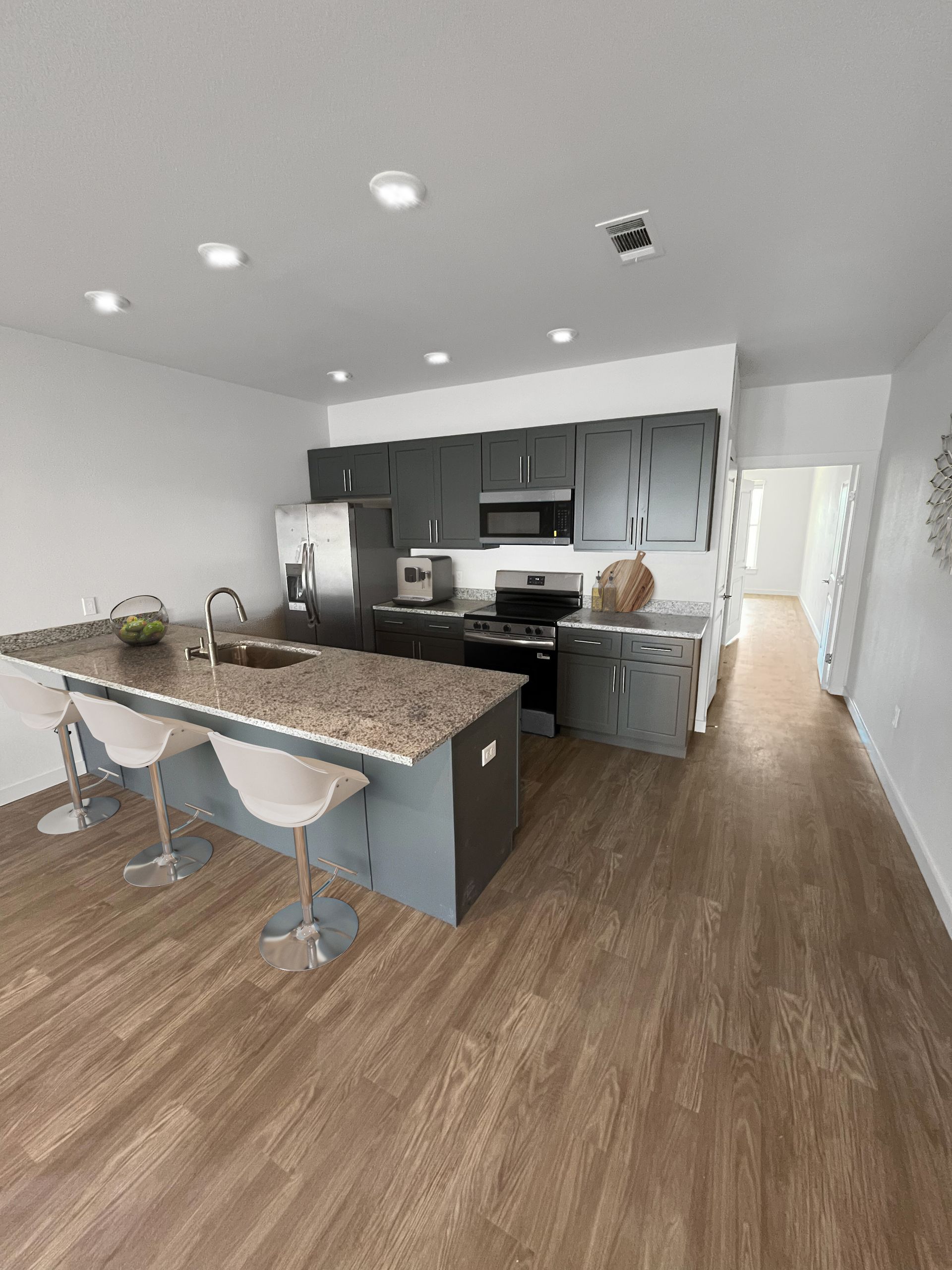 A kitchen with stainless steel appliances , granite counter tops , and hardwood floors.