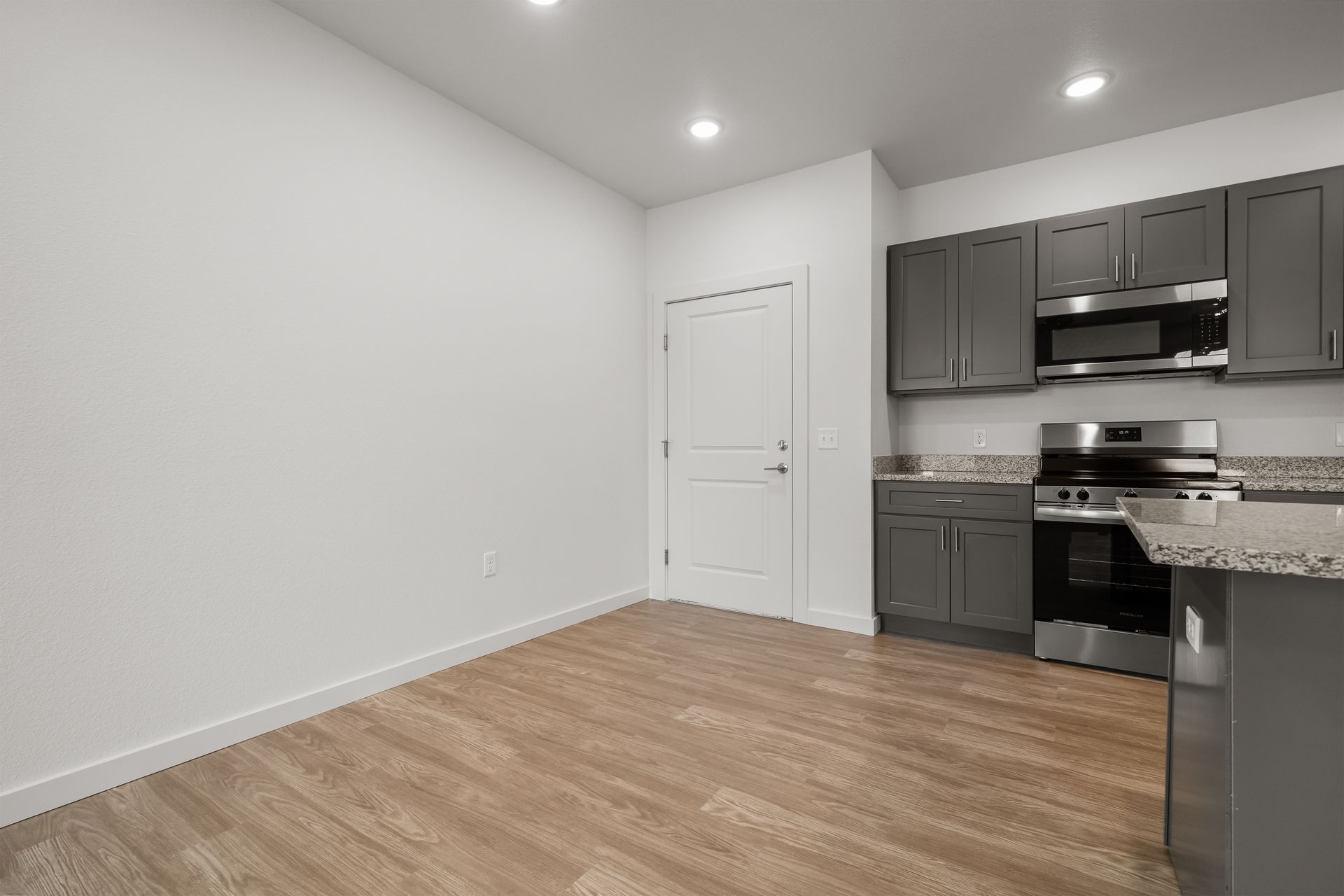 An empty kitchen with gray cabinets and stainless steel appliances.