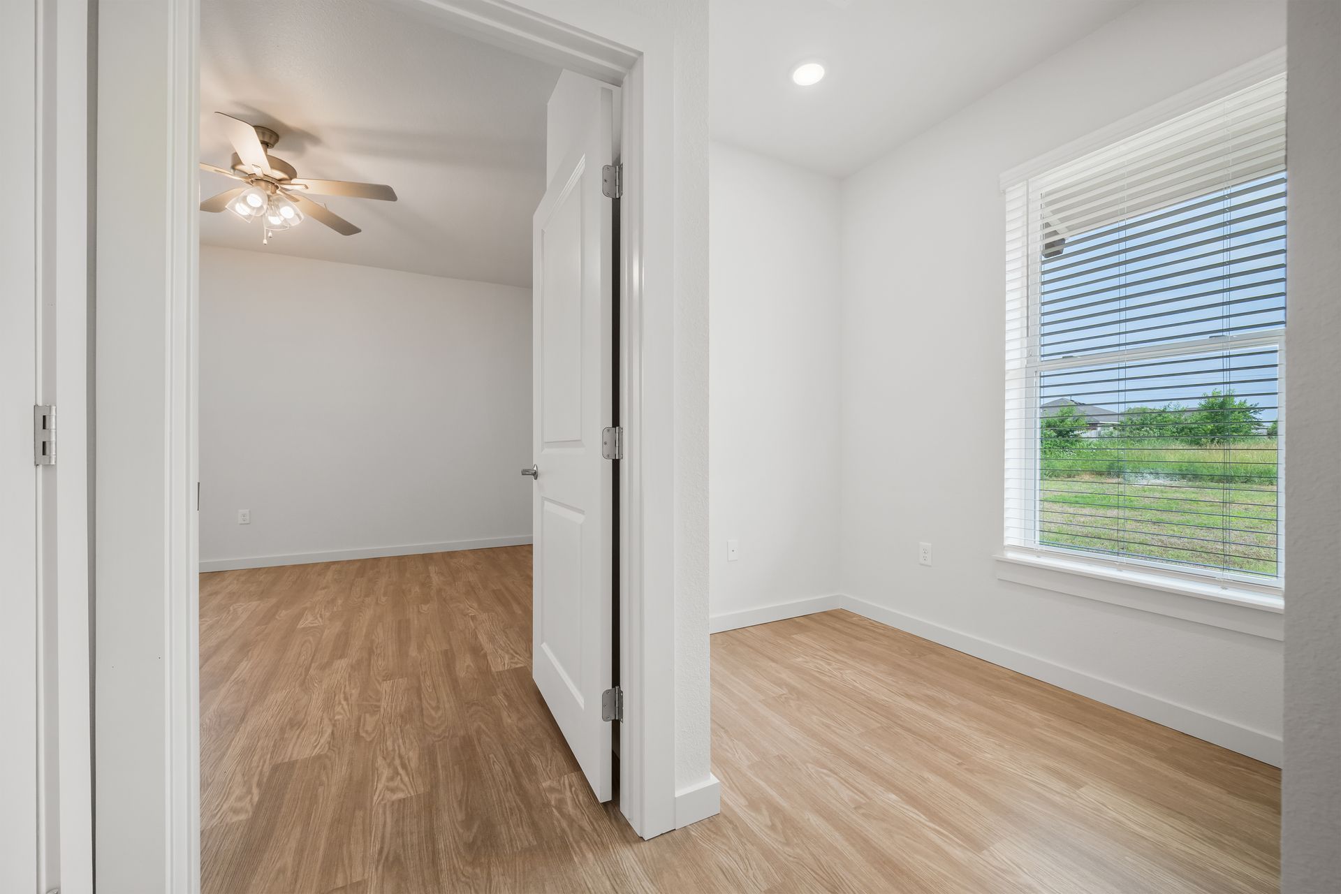 An empty bedroom with hardwood floors and a ceiling fan.