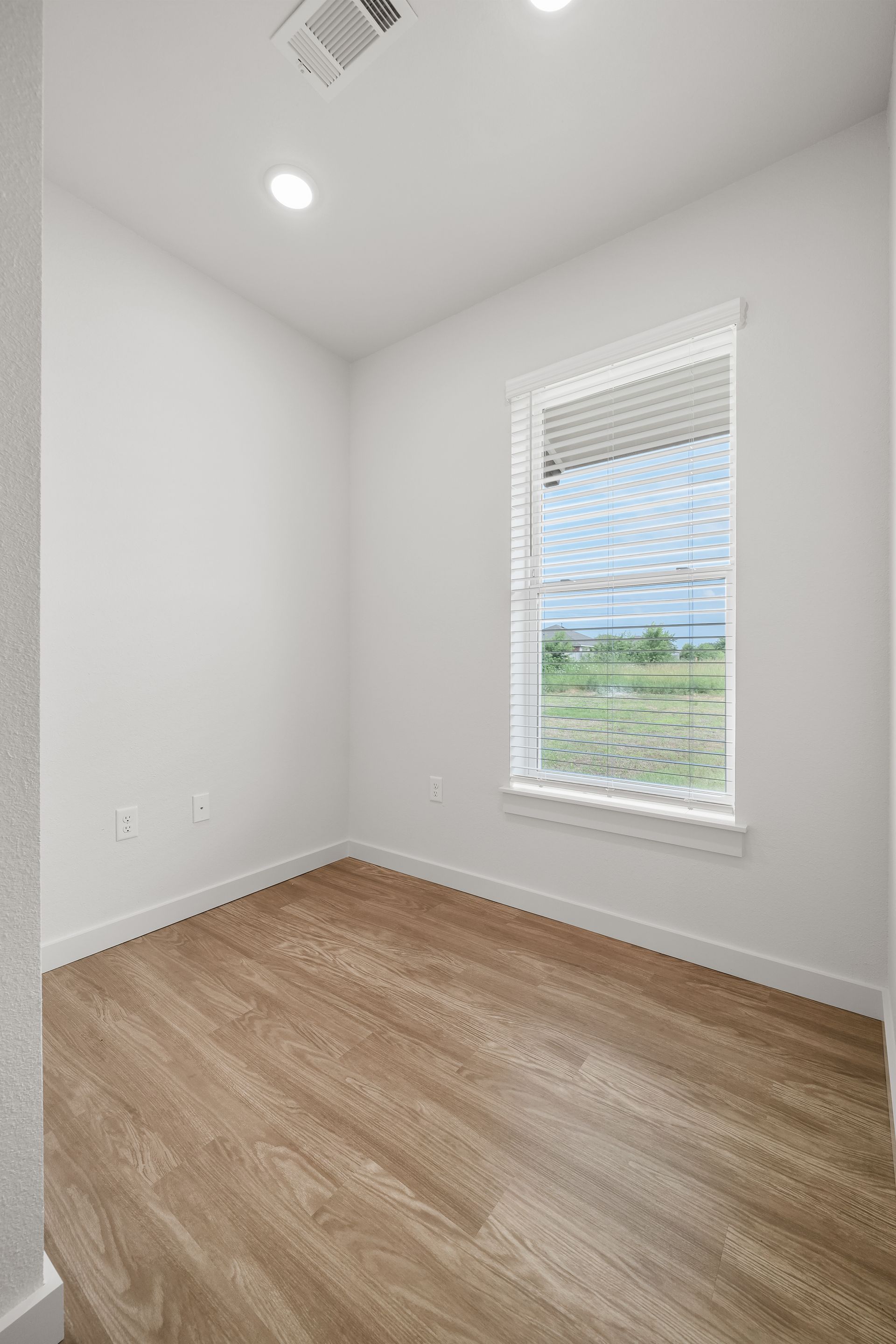 An empty room with hardwood floors and a window.