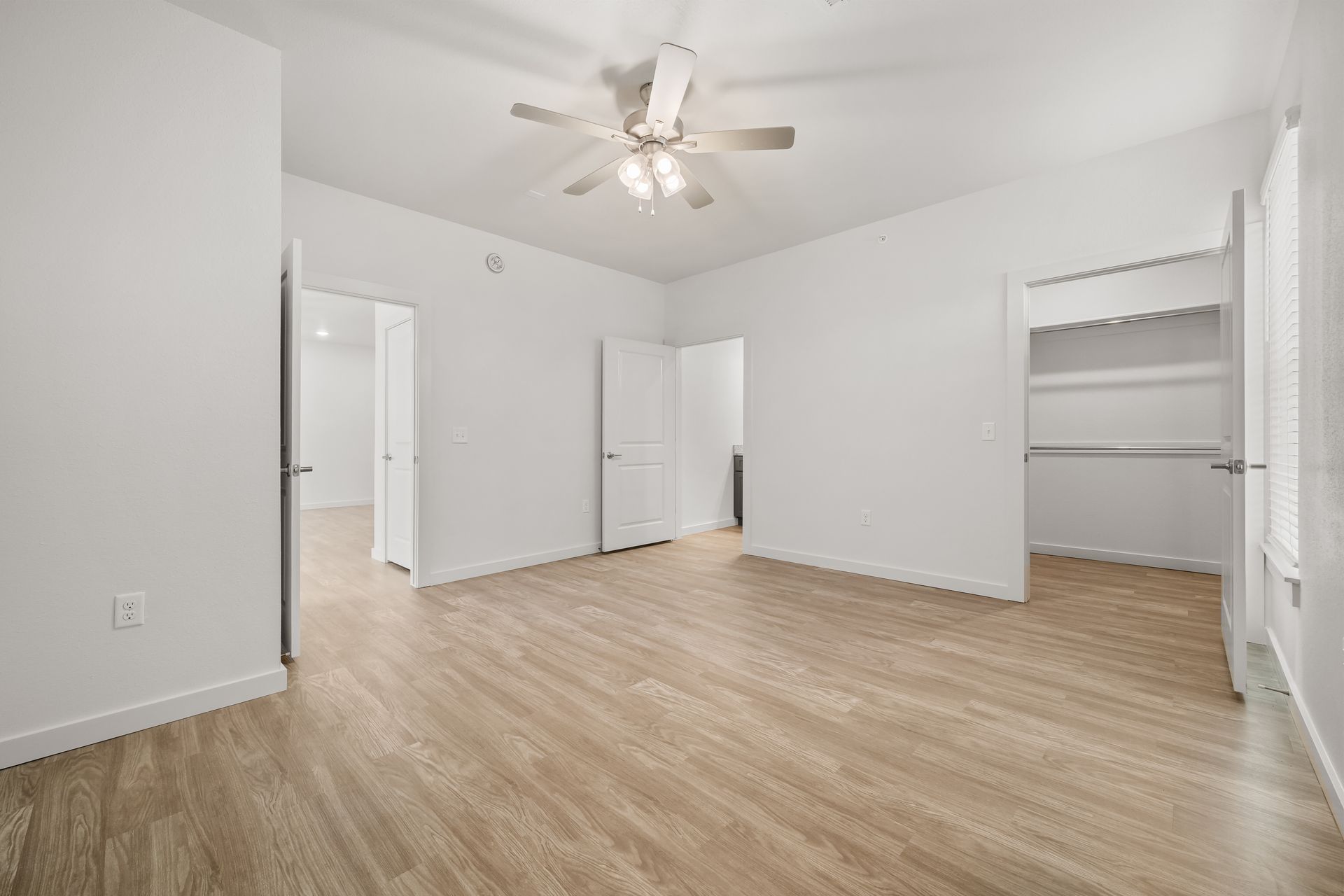 An empty bedroom with hardwood floors and a ceiling fan.