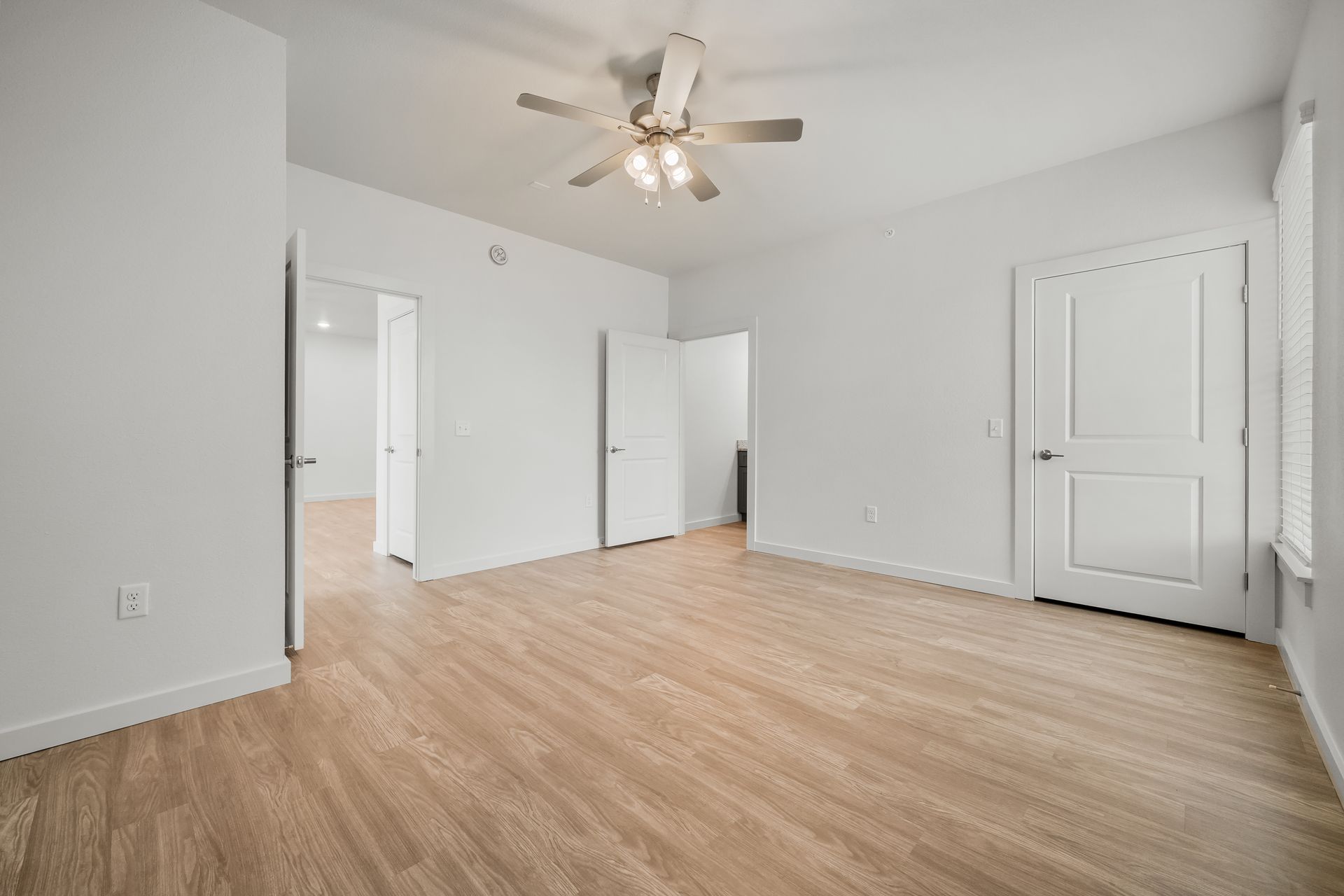 An empty room with hardwood floors and a ceiling fan.