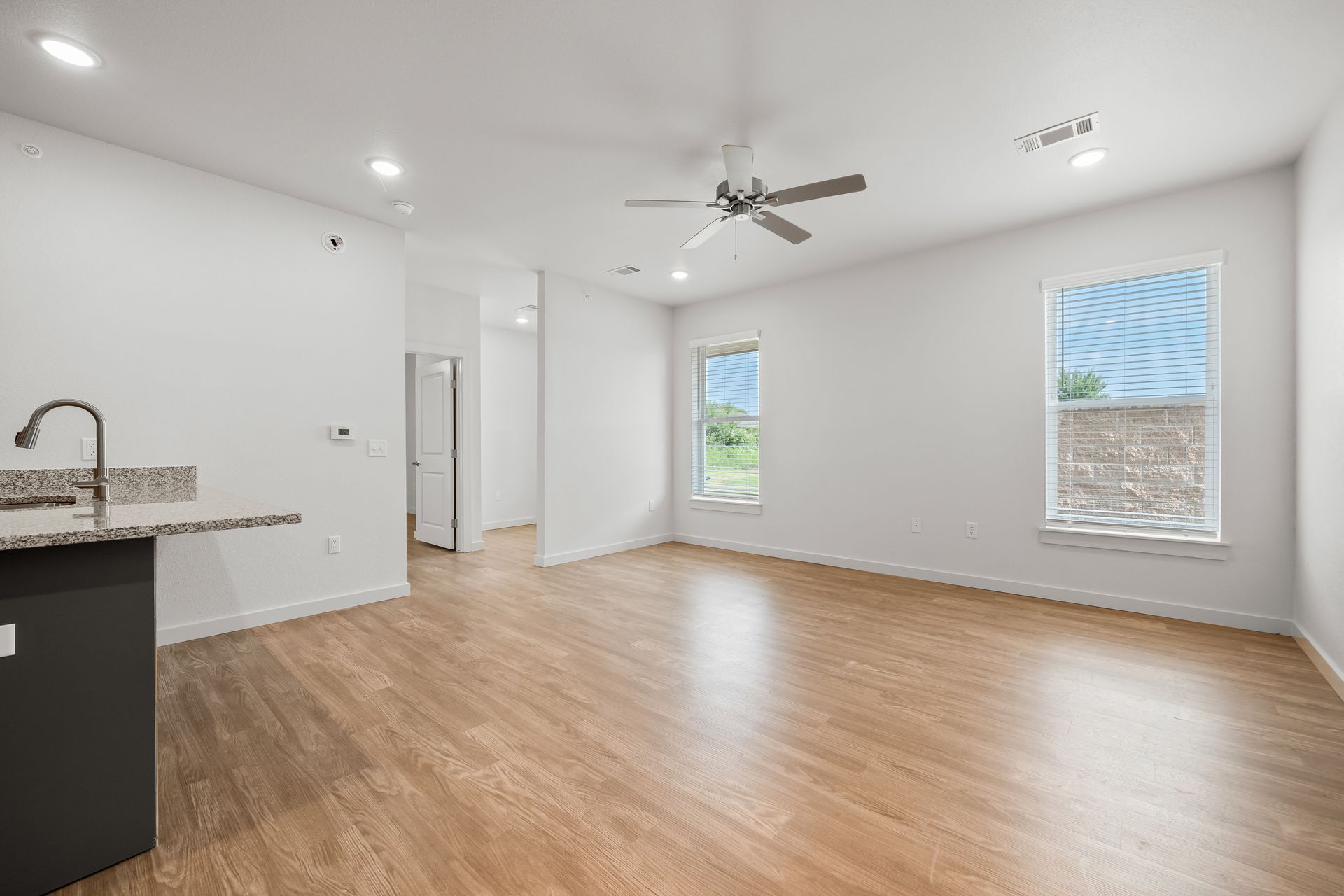 An empty living room with hardwood floors and a ceiling fan.