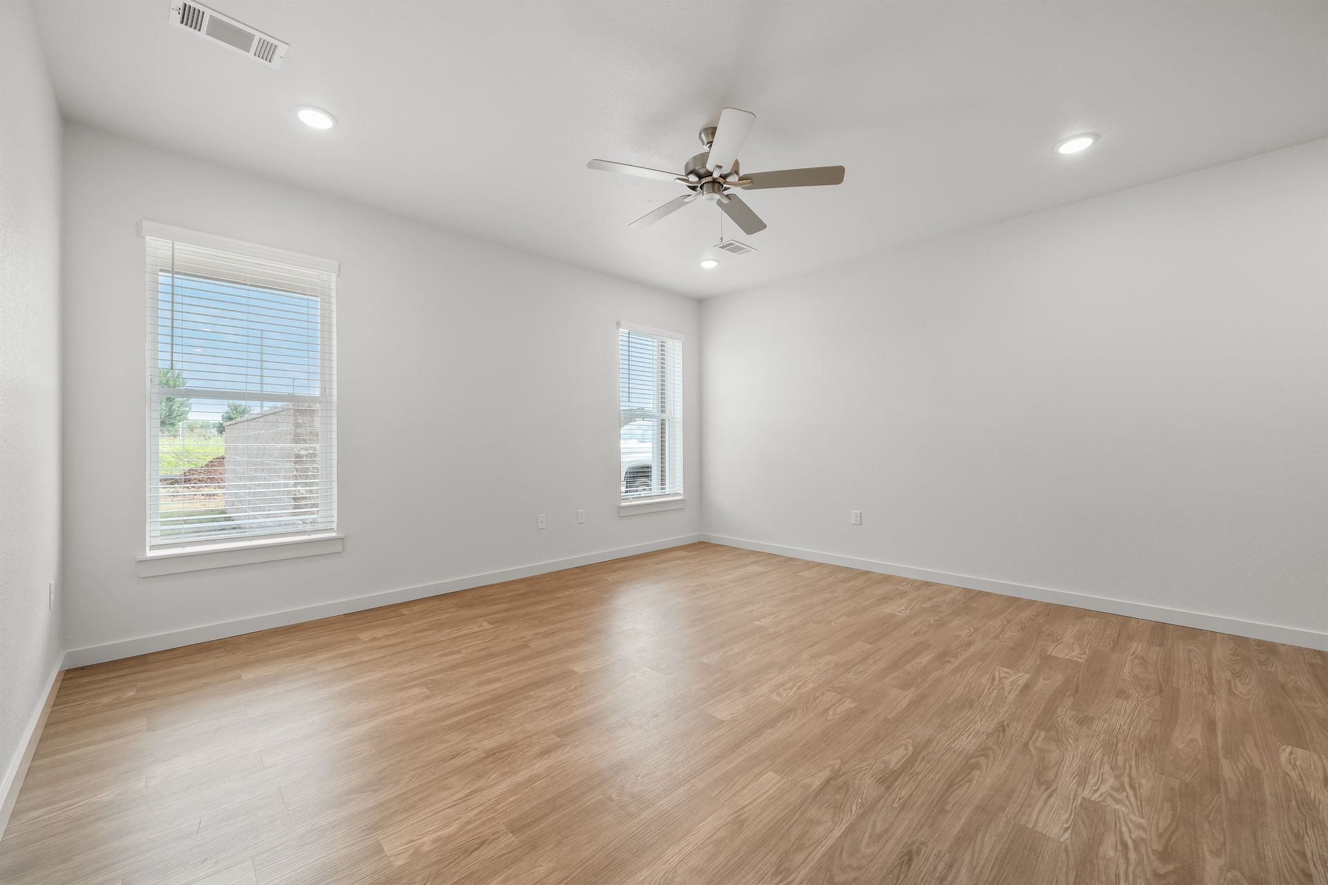 An empty room with hardwood floors and a ceiling fan.