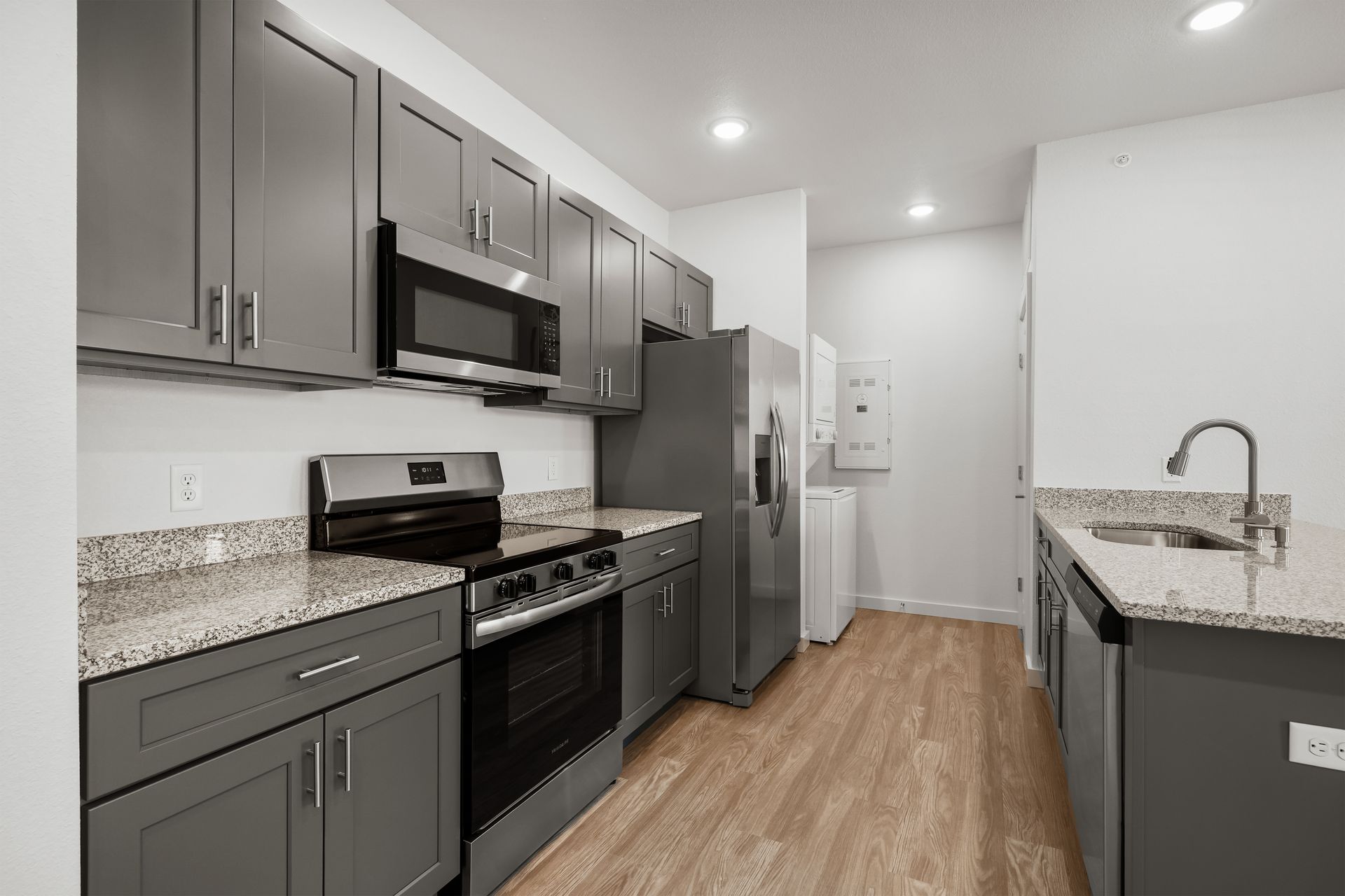 A kitchen with gray cabinets , stainless steel appliances and granite counter tops.