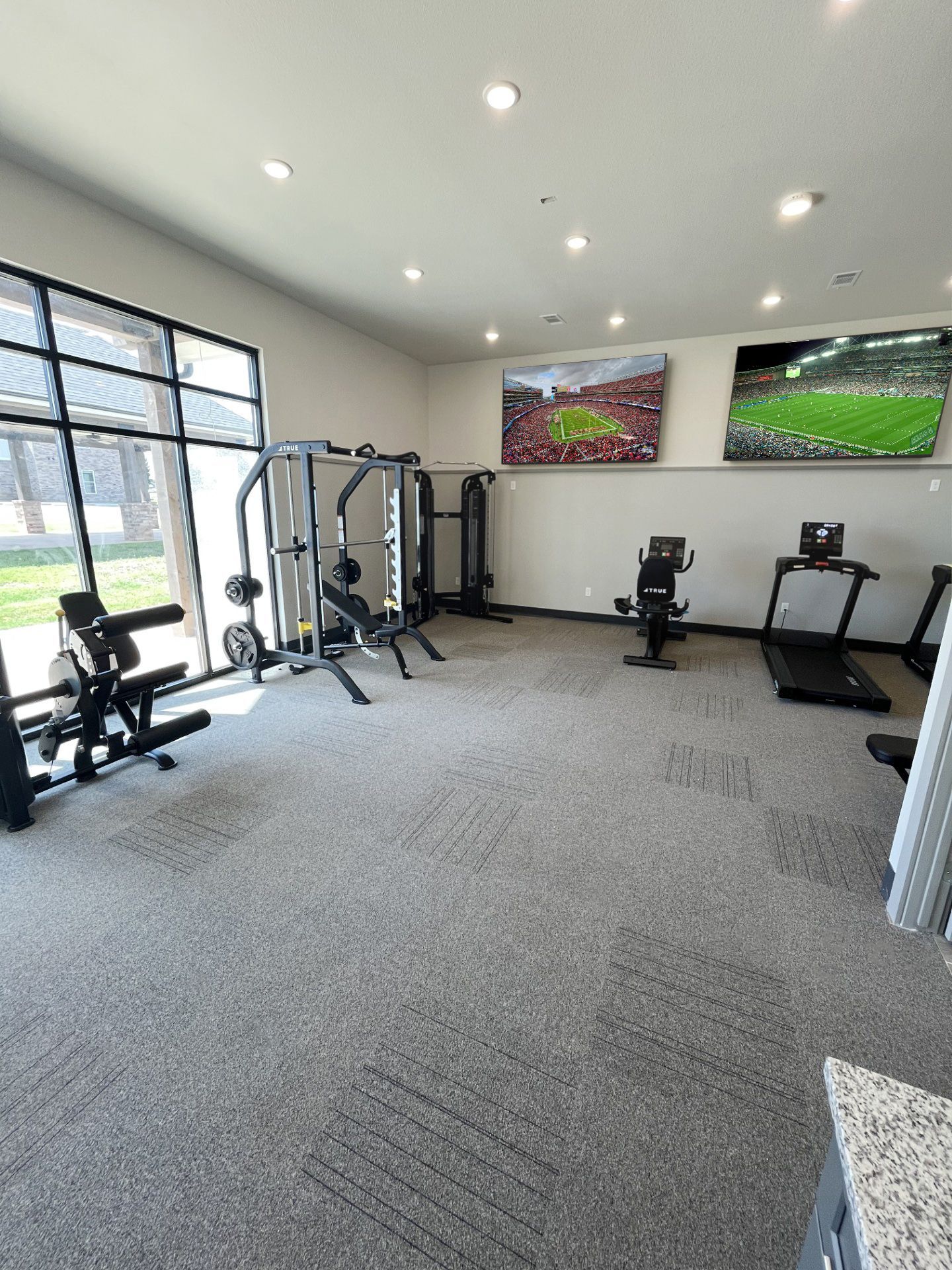 A gym with a lot of equipment and a television on the wall.
