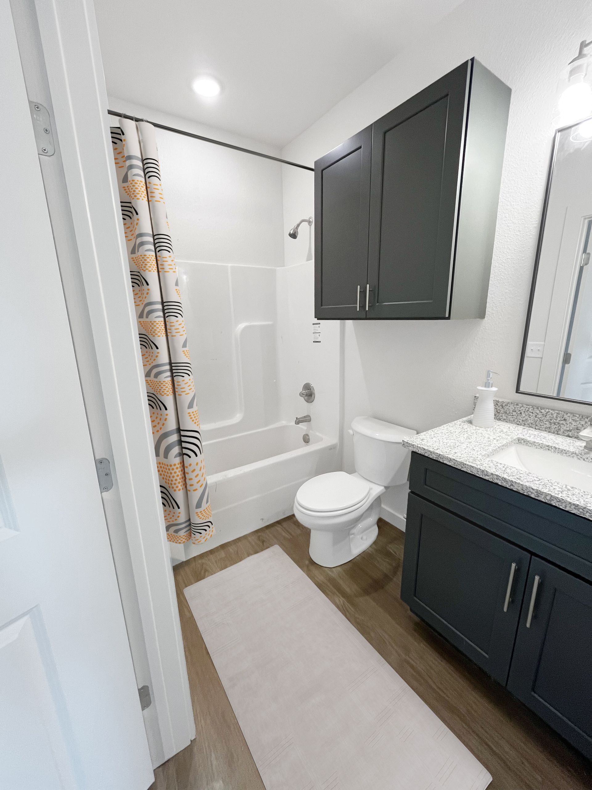 A bathroom with a toilet , sink , bathtub and shower curtain.