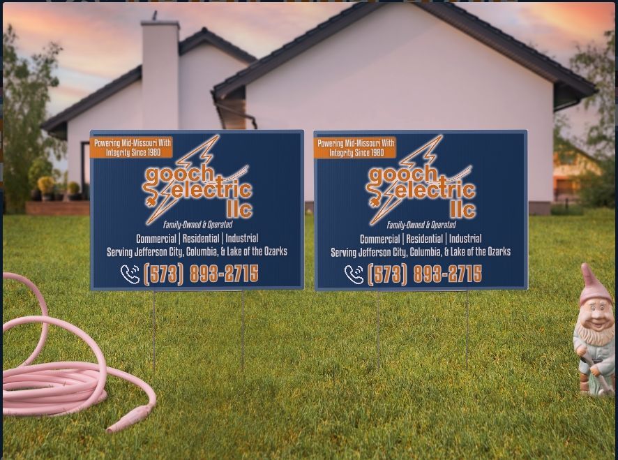 Two Gooch Electric LLC signs in a grassy yard in front of a house, featuring contact info, a lightning bolt logo
