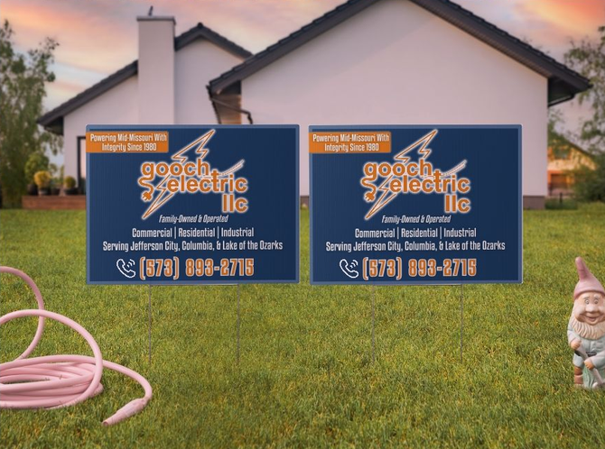 Two identical Gooch Electric LLC lawn signs in a grassy yard in front of a house, featuring a lightning bolt logo and phone.