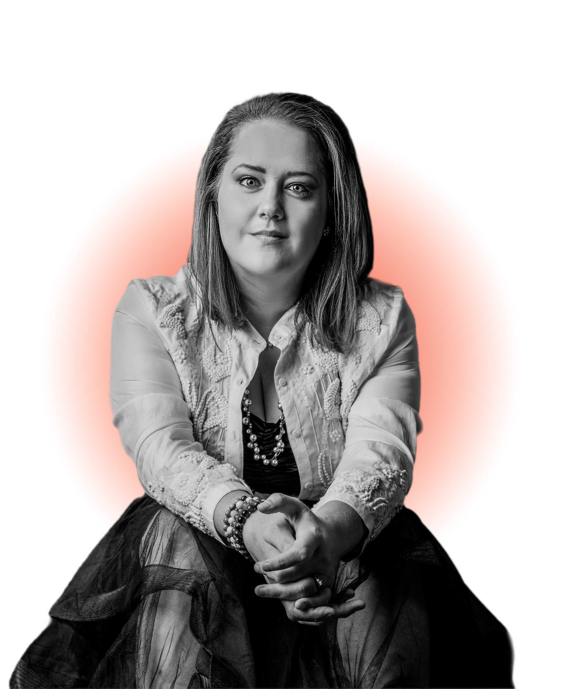 Woman in lacy jacket and black skirt, seated, hands clasped, with red glow behind.