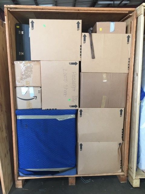 Wooden crate packed with various cardboard boxes and a blue-covered object.