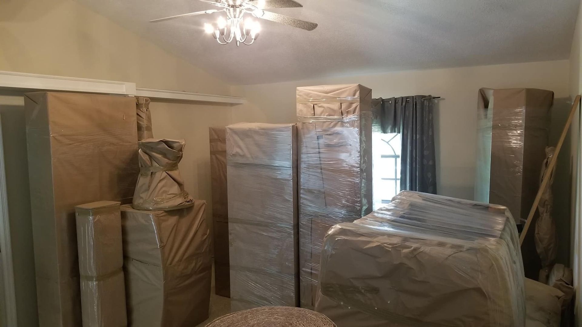 Room full of furniture wrapped in protective coverings, ready for a move.