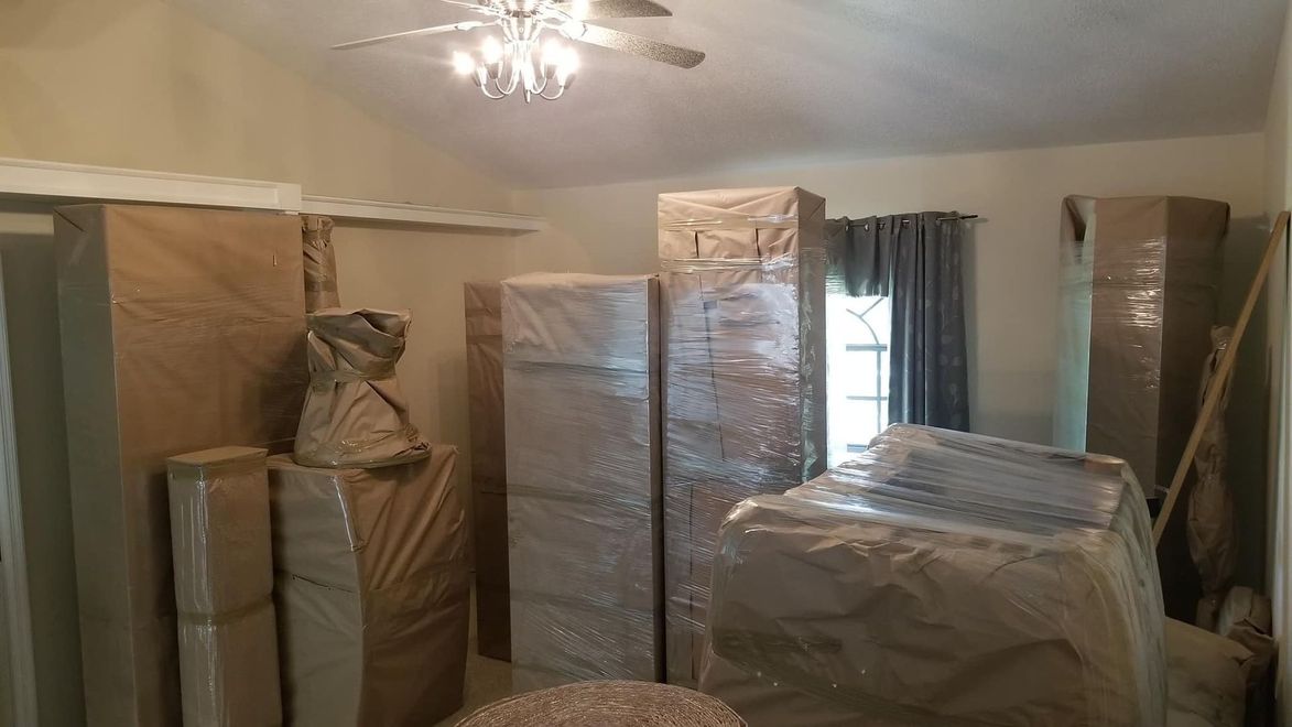 Room full of furniture wrapped in protective coverings, ready for a move.