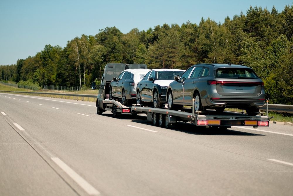 A moving truck with an open back, parked on a residential driveway, packed with cardboard boxes and household furniture.