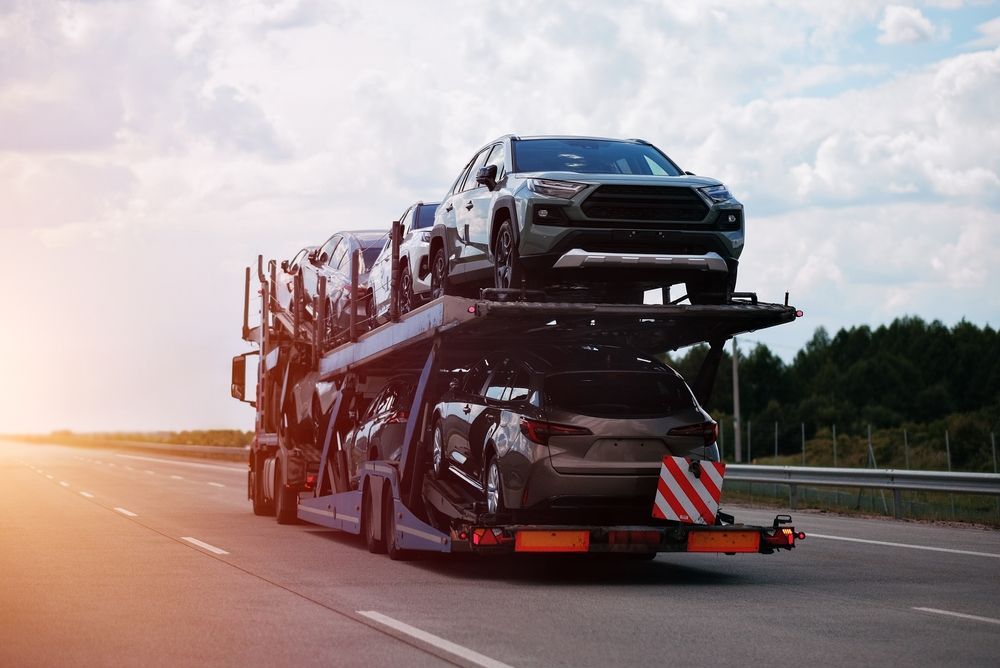 A view through an open doorway of a moving truck filled with boxes, furniture, and a potted plant.