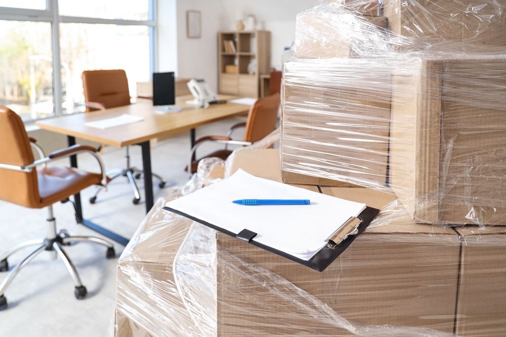 A view through an open doorway of a moving truck filled with boxes, furniture, and a potted plant.