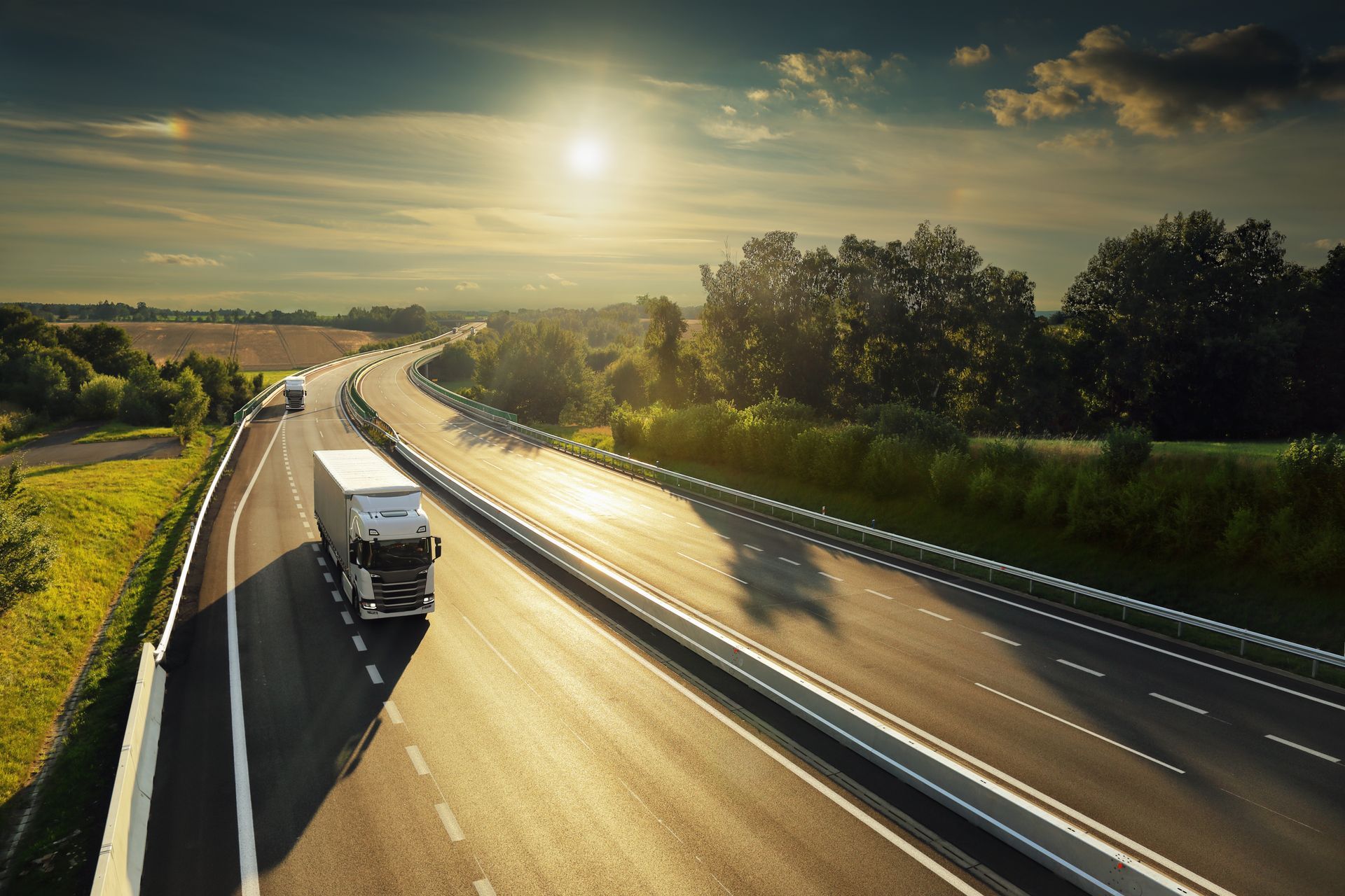 A moving truck with an open back, parked on a residential driveway, packed with cardboard boxes and household furniture.