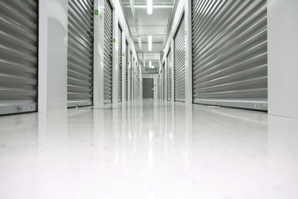 A moving truck with an open back, parked on a residential driveway, packed with cardboard boxes and household furniture.