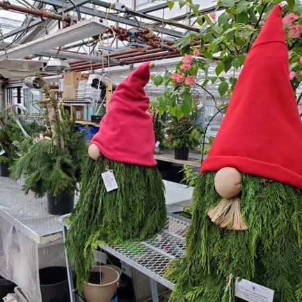 Plant urns that are decorated to look like elves with red hats.