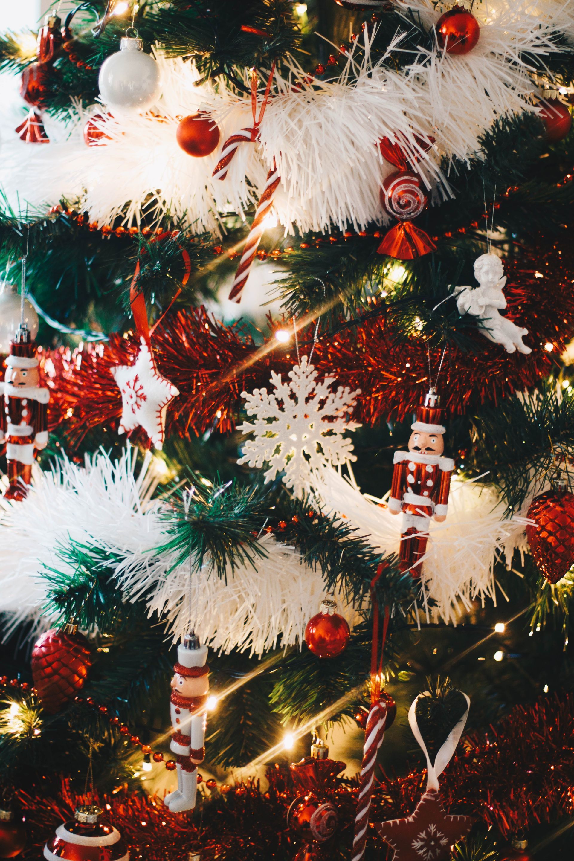 A Christmas tree with white tinsel and red and white ornaments.