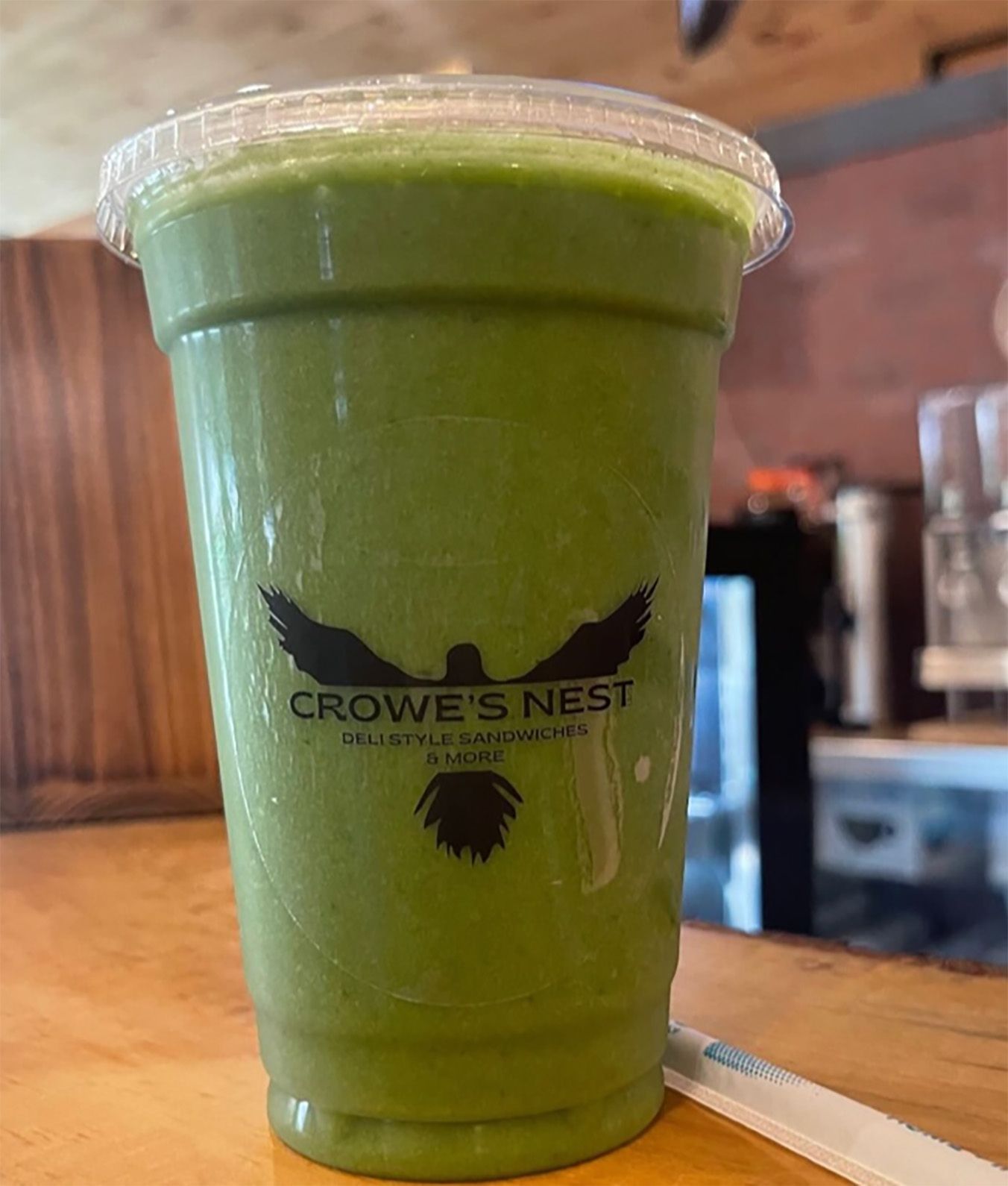 A green smoothie in a plastic cup with a bird on it.