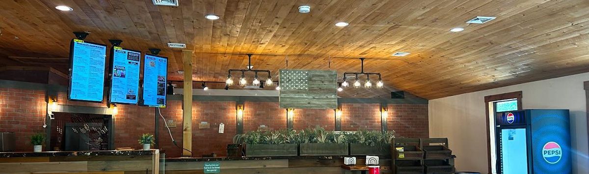 A restaurant with wooden tables and chairs and a wooden ceiling.