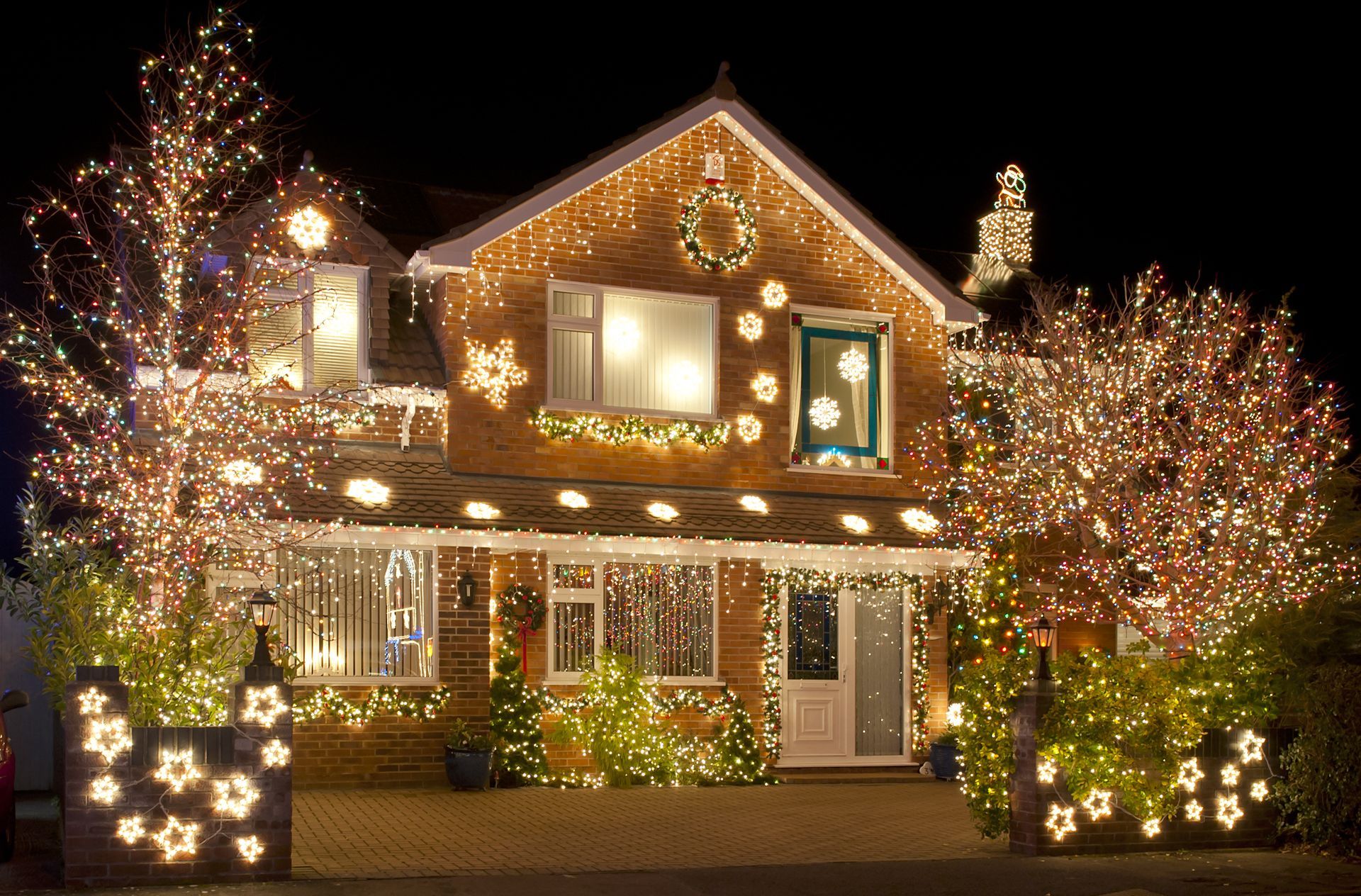 House covered in glowing christmas lights and decorations at night