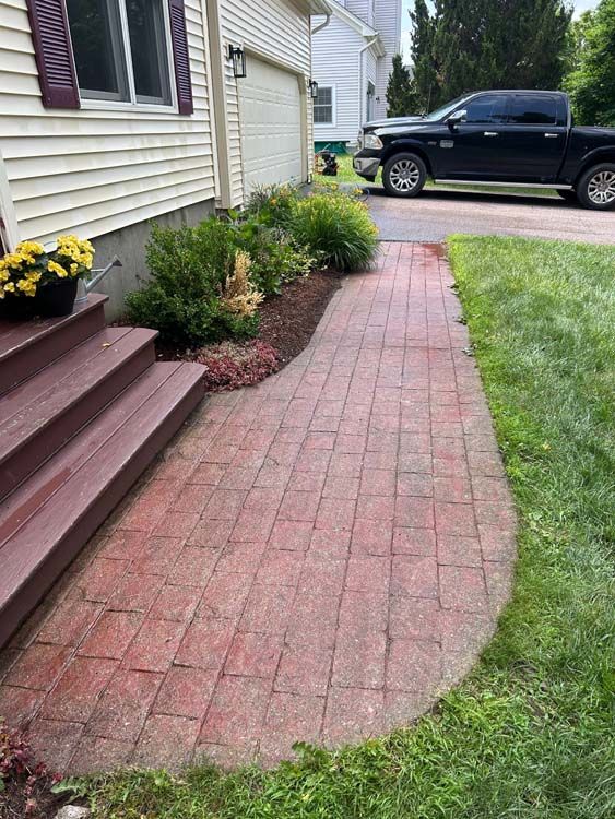 Brick walkway leading from wooden steps to a driveway