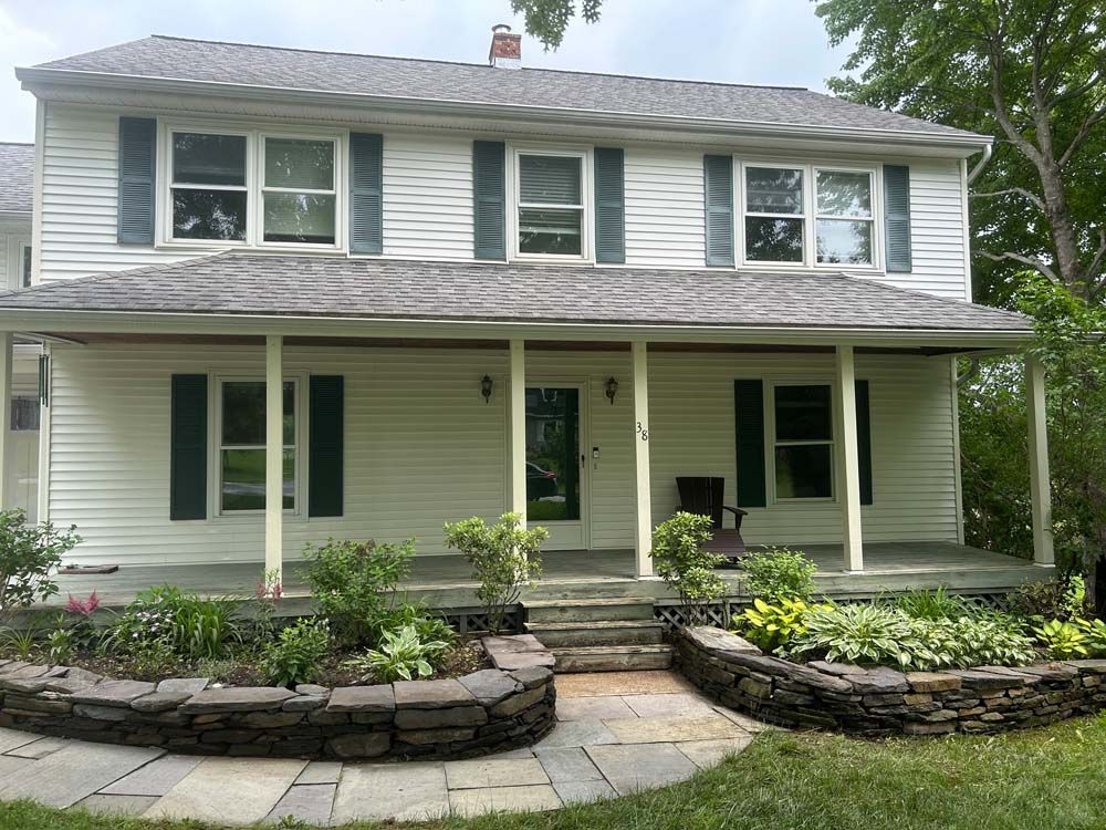 Two-story white house with green shutters and a porch