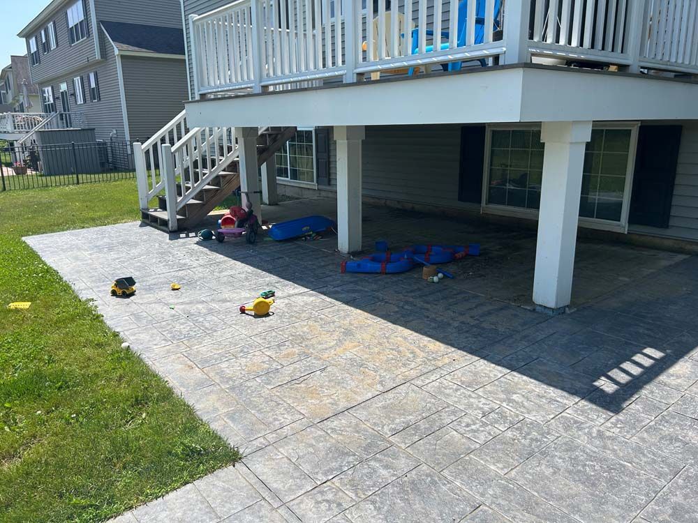 Concrete patio under a deck with toys scattered