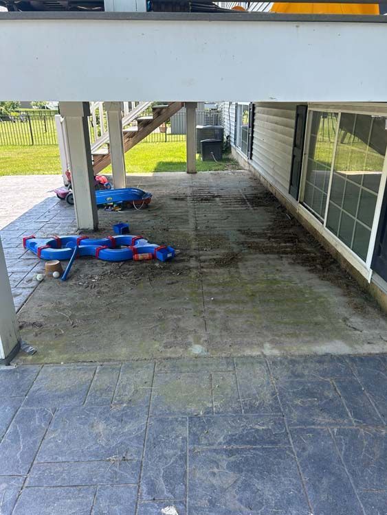 Concrete patio under deck with toys and staining