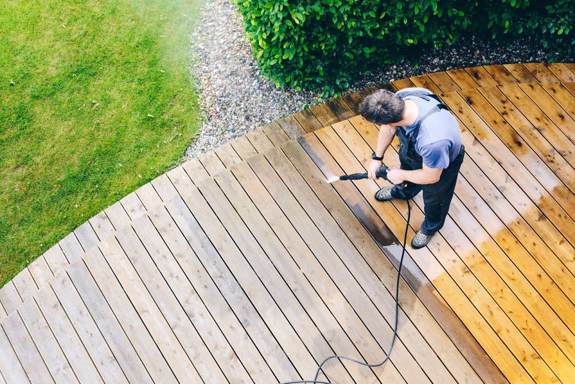 Person power washing a wooden deck