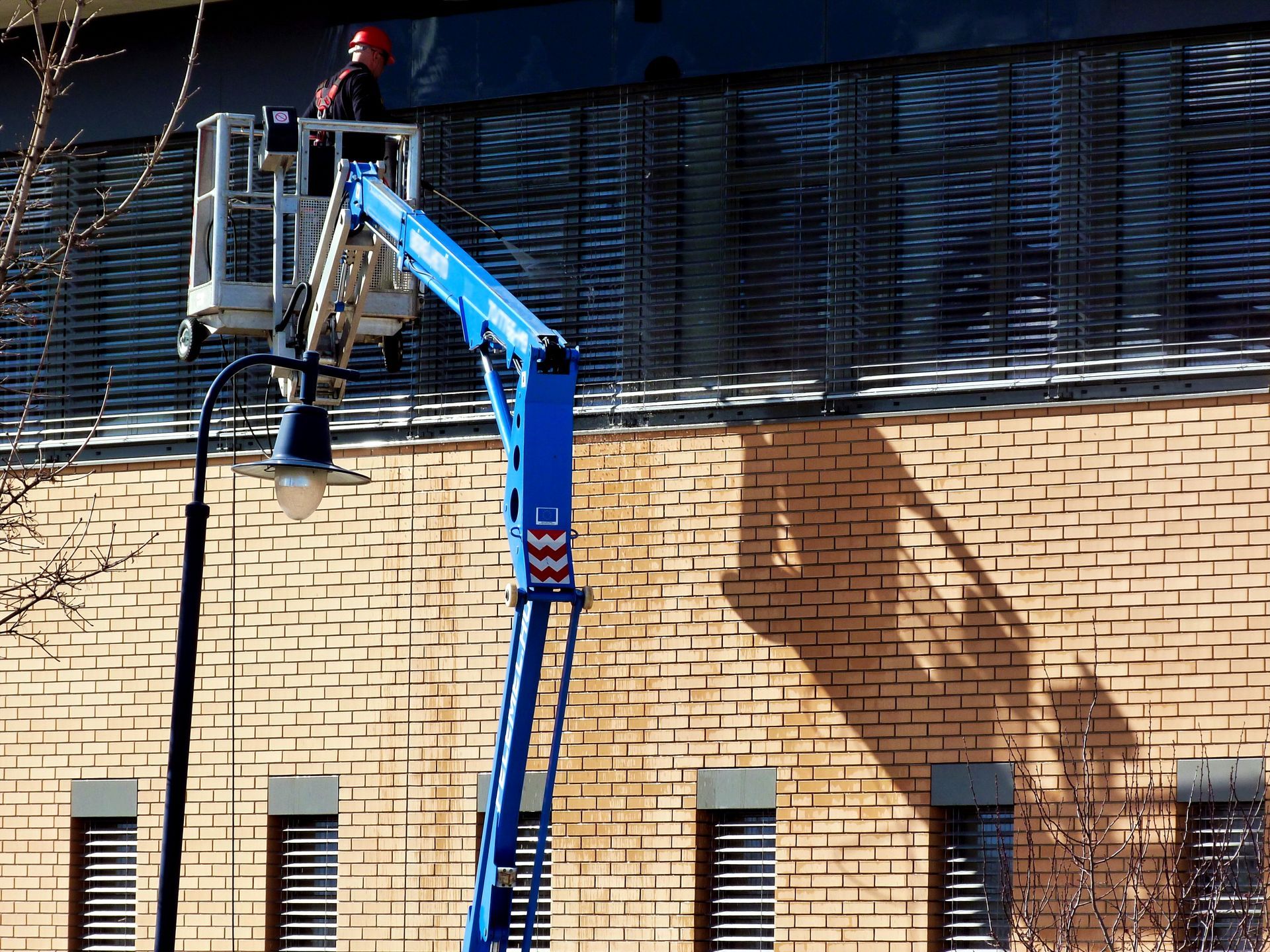 Person in a cherry picker working on the exterior of a brick building