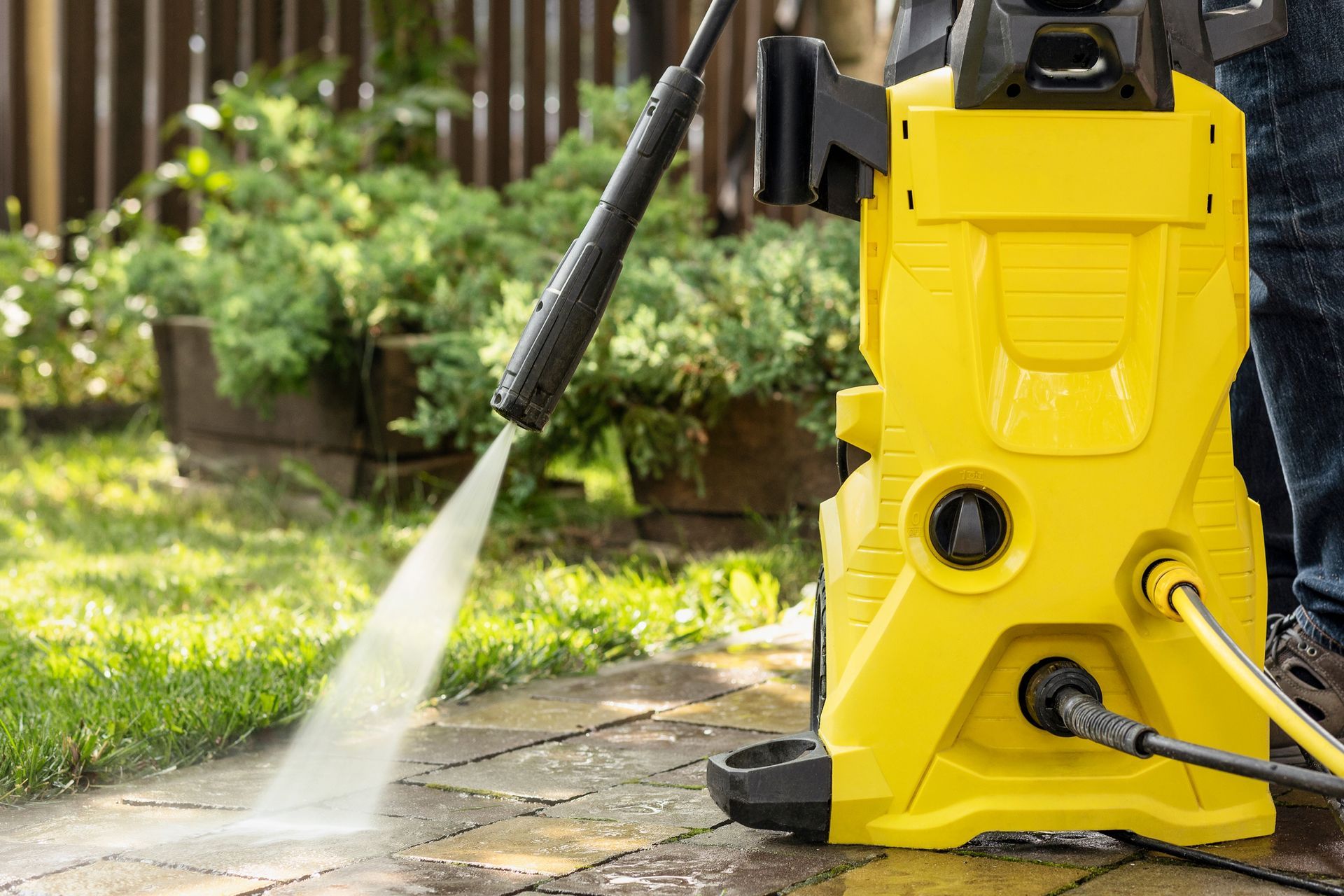 Yellow pressure washer cleaning a brick patio