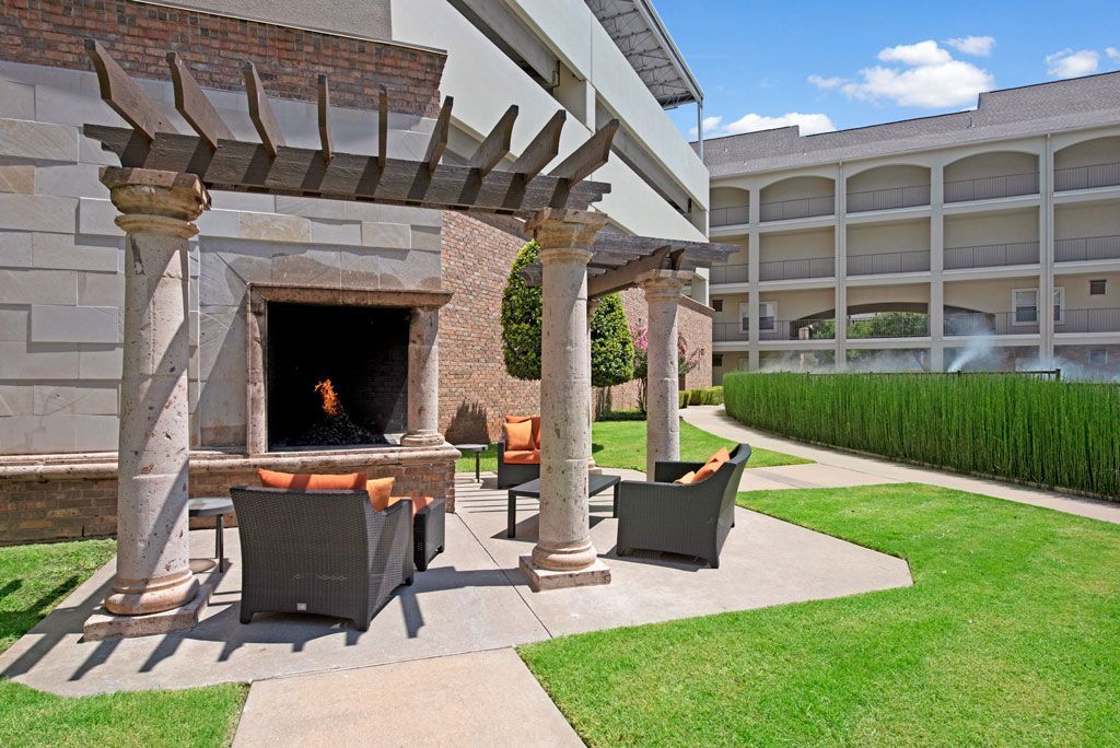 A patio with a fireplace and chairs under a pergola