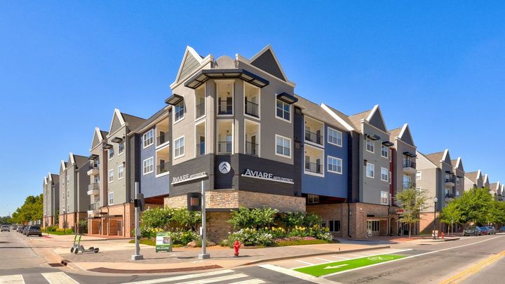 A large apartment building is sitting on the corner of a city street.