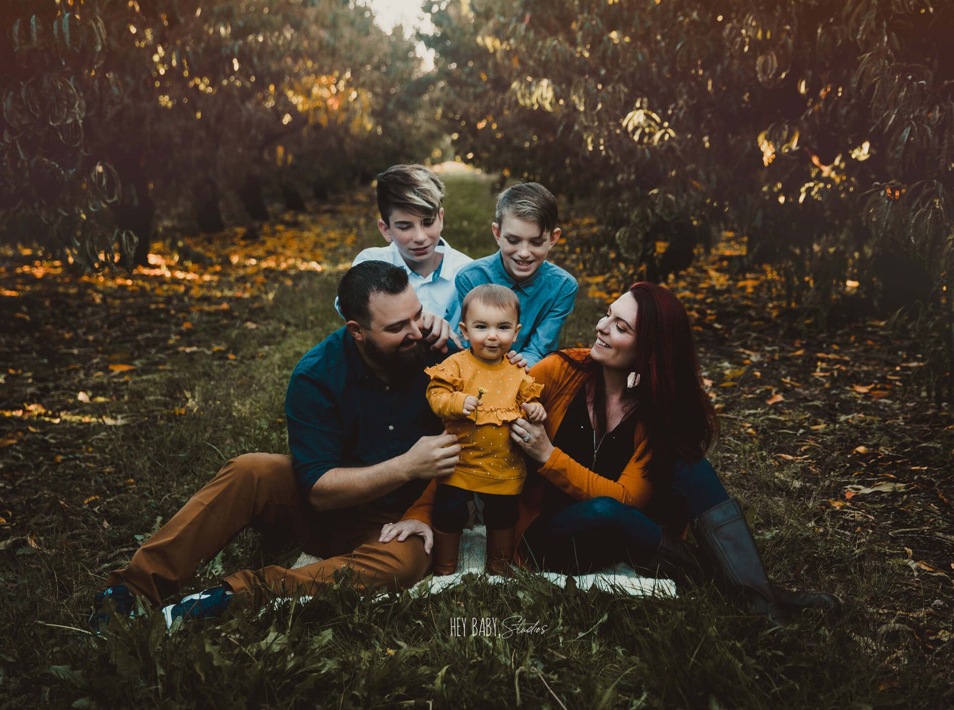 A family is sitting on the grass in a field.