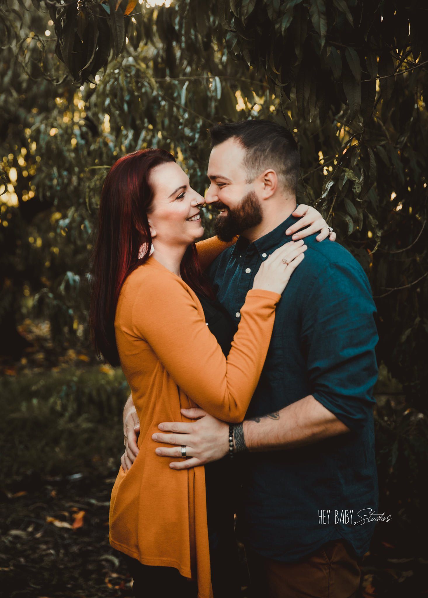 A man and a woman are hugging each other in the woods.