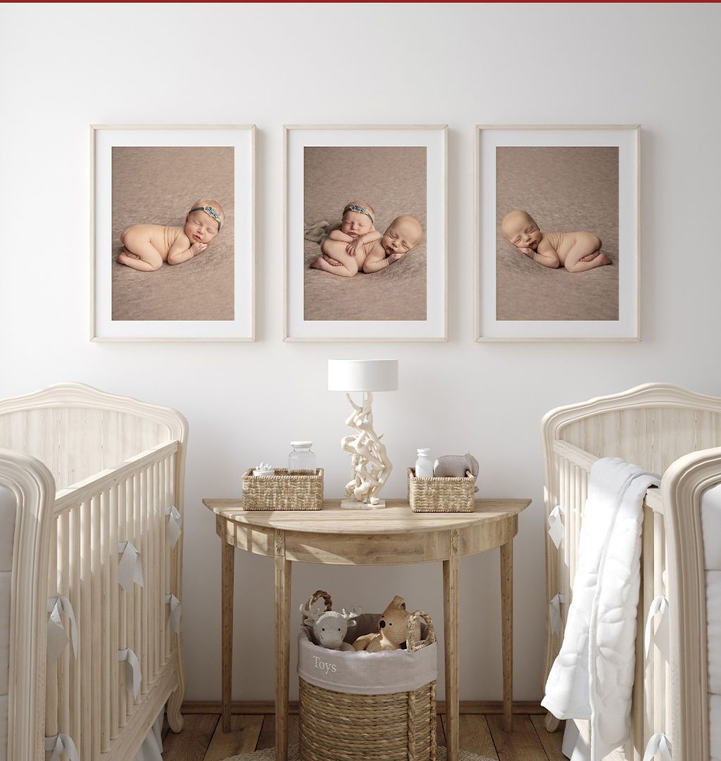 A nursery with two cribs and three pictures of babies on the wall.