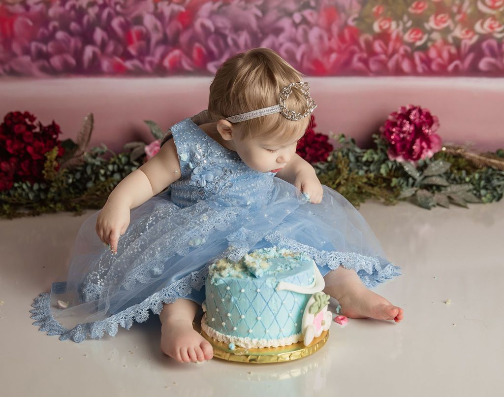 A little girl in a blue dress is eating a blue cake.