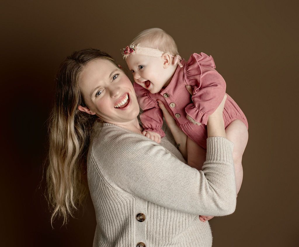 A woman is holding a baby in her arms and smiling.