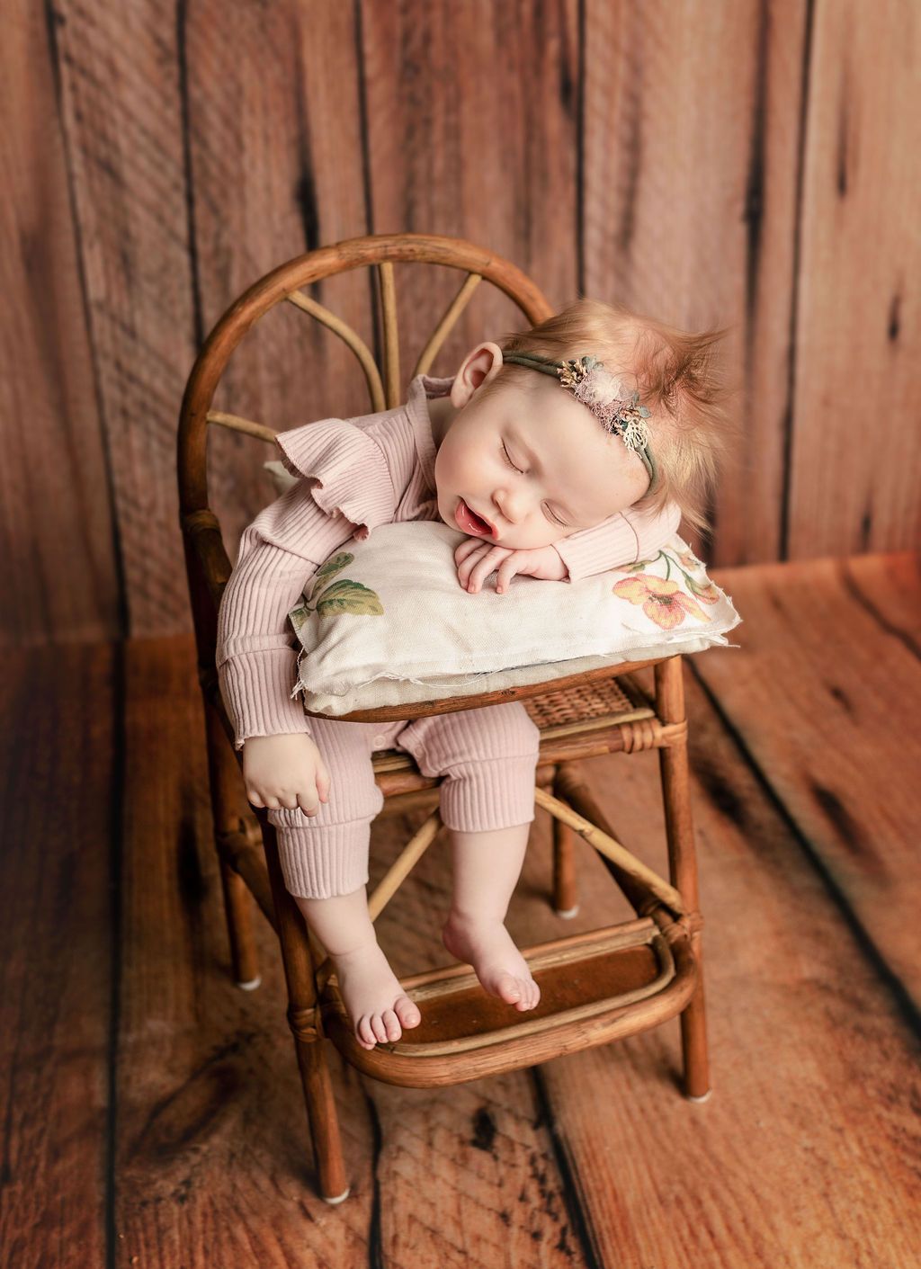 A baby is sleeping on a pillow in a high chair.