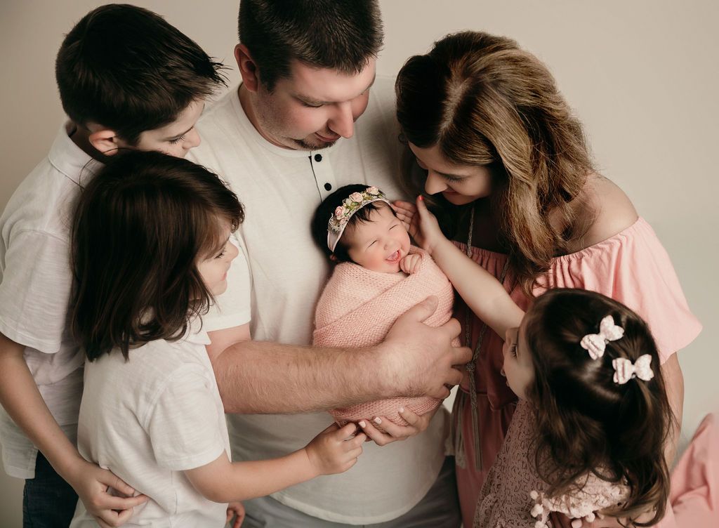 A family is holding a newborn baby in their arms.